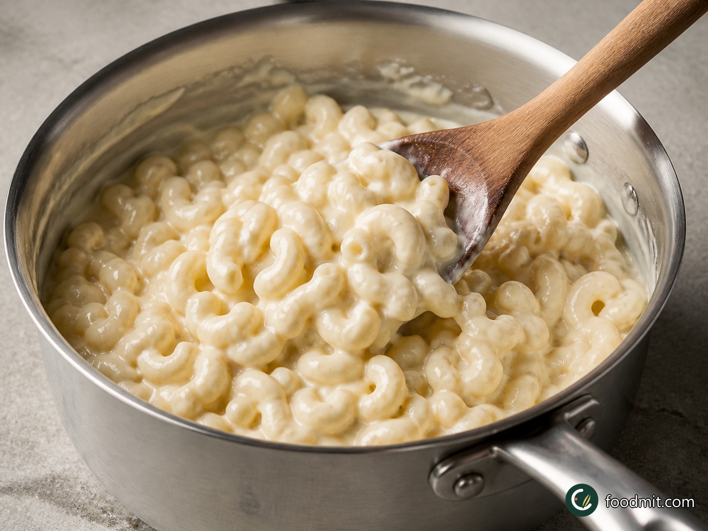 Add the remaining grated white cheddar a little at a time, stirring after each addition so it melts evenly into the cream-cheese base. Continue over medium-low heat for about 5 minutes, until the sauce is cohesive and no shreds of cheddar remain. Add the drained macaroni, ¼ teaspoon salt, and ⅛ teaspoon pepper, then turn and fold until every elbow is coated.