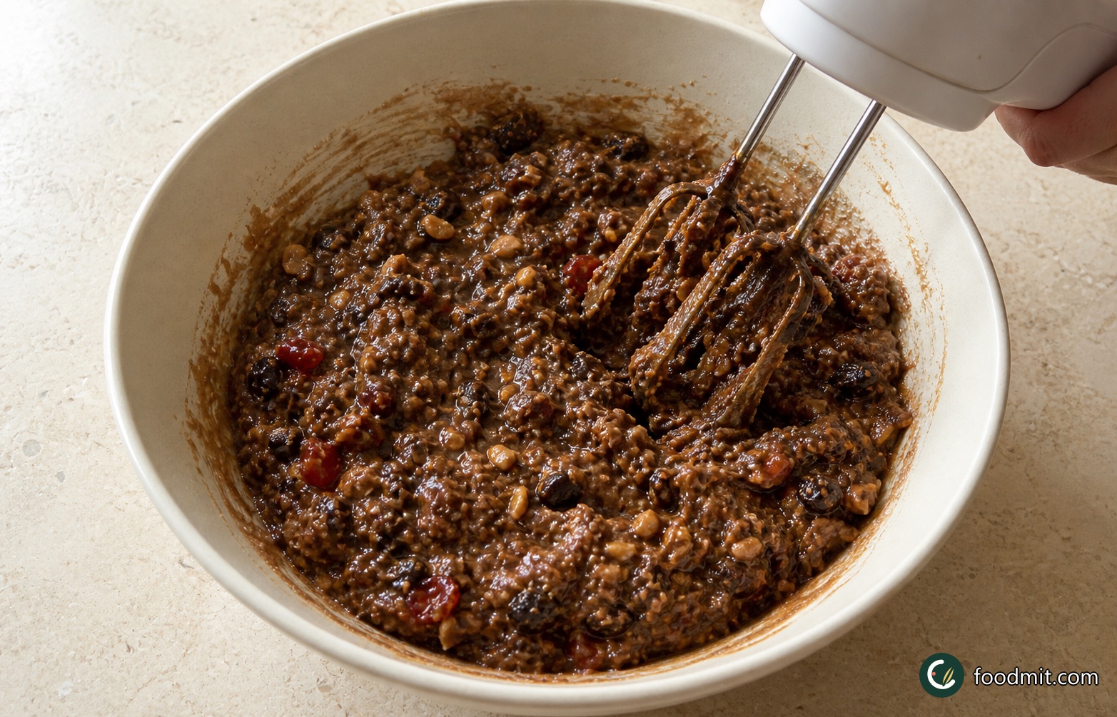 Transfer the soaked fruit and every drop of liquid to a roomy mixing bowl. Add the sifted self-raising flour, mixed spice, baking powder, softened butter, dark muscovado sugar, orange zest, lemon zest, chopped Brazil nuts, mixed chopped nuts, and eggs. Beat everything together with an electric hand mixer for about 1 minute, or work vigorously with a wooden spoon, until no pockets of dry flour remain and the fruit is evenly distributed. Because everything enters the bowl together, it helps to check off each ingredient as you add it.
